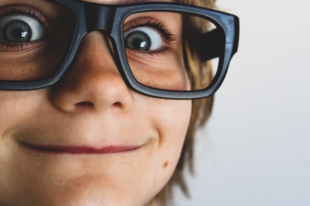 Barriers to Pediatric Hearing Aids kid wearing glasses