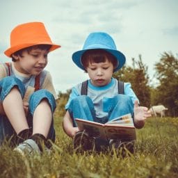 kids reading a book in a field