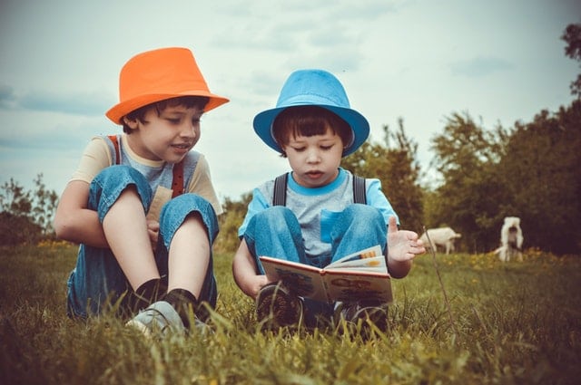pediatric hearing loss kids reading a book in a field