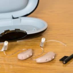 Close up of hearing aids with hearing aid cleaning kit.