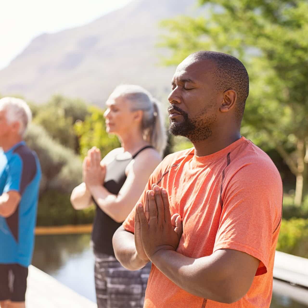 Man breathes peacefully during a silent group meditation class in a sunny park