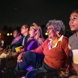 Family attending the Kentucky Shakespeare Festival sits in their seats, enjoying the show.