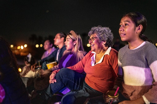 Family attending the Kentucky Shakespeare Festival sits in their seats, enjoying the show.