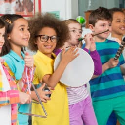 Young Children in a Row Holding Different Instruments and Performing in Music Class